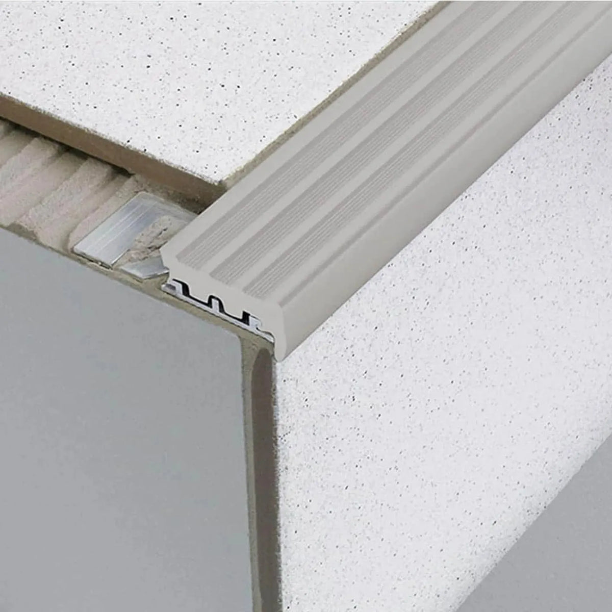 profilé d'escalier encastré sous le carrelage avec un large insert en caoutchouc gris. Une partie de l'aile estampée est libre dans le lit de colle. #FR0001753
#FR0001757