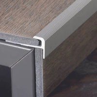 profilé de nez de marche en forme de F en aluminium monté sur la marche, avec sol en vinyle inséré verticalement et horizontalement.
