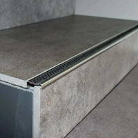 Profilé de nez de marche en aluminium antidérapant posé avec insert noir nuit sur une marche carrelée grise #A0001724
#A0002701